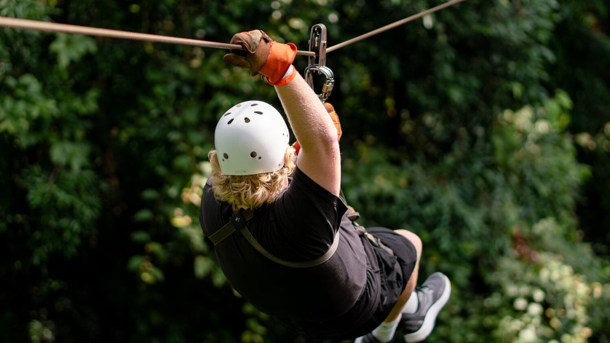 Zipline participant crossing the canopy at Vista Los Sueños, Herradura