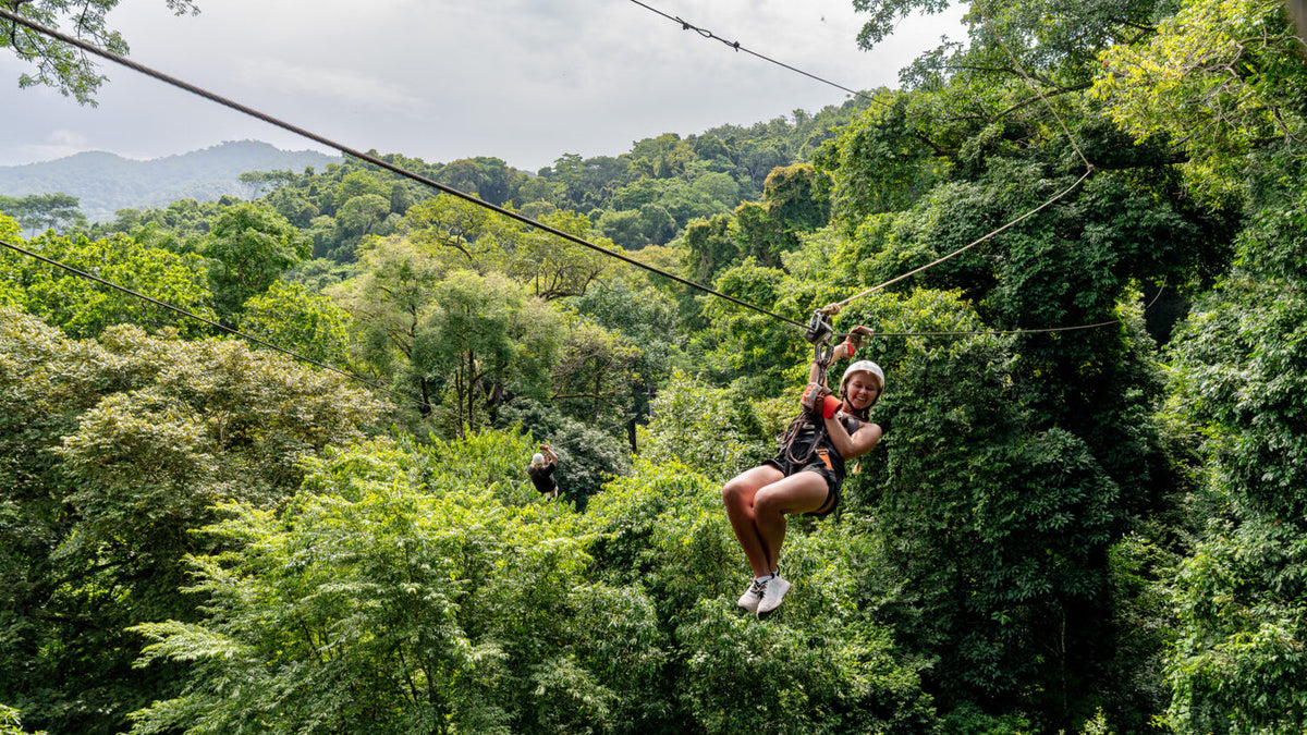 Zipline rider above the rainforest canopy at Vista Los Sueños
