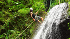 Canyoning participant rappelling beside a waterfall at Vista Los Sueños