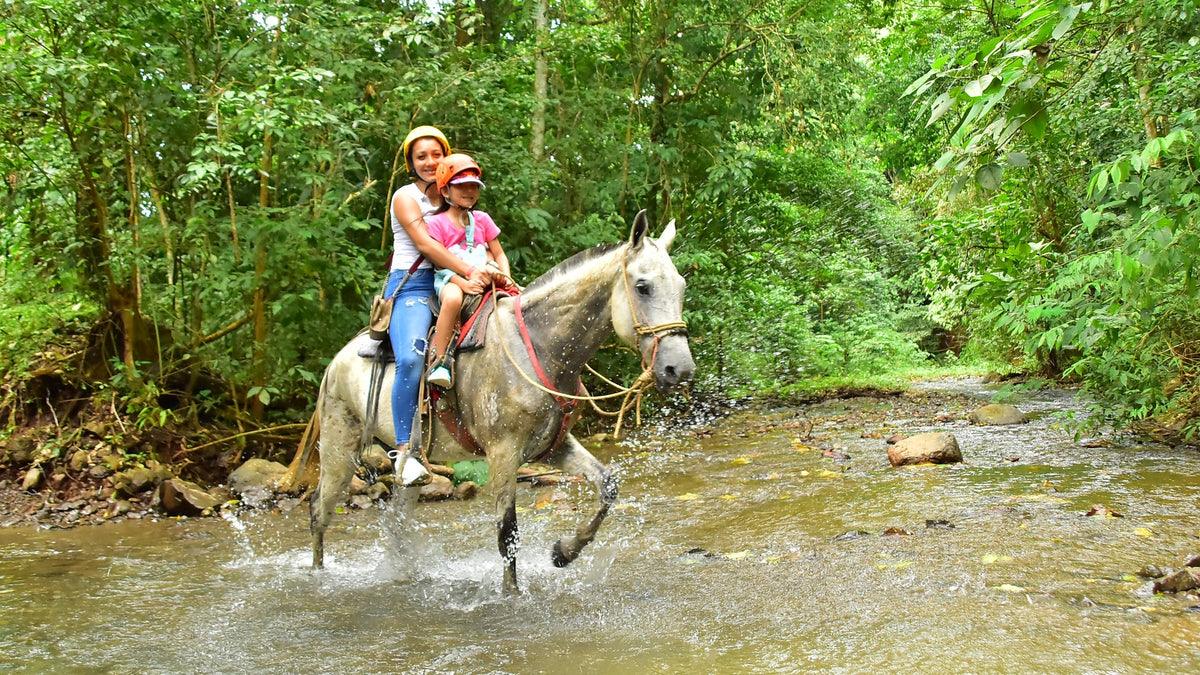 Horseback riders crossing a river at Vista Los Sueños, Herradura