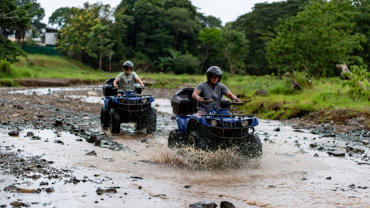 ATV riders crossing a shallow river at Vista Los Sueños